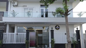 A hotel entrance with a glass door, a signboard, and a gated entrance. - Opulent Inn By Lime Tree Hotels (Greater Noida)