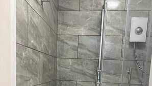 Un baño con inodoro, ducha y puerta de cristal.