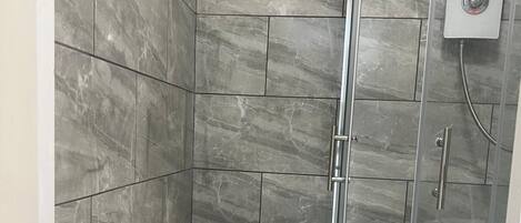 A bathroom with a toilet, a shower, and a glass door.