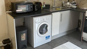 Cocina compacta con microondas, tostadora, lavabo y lavadora.