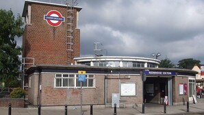 A brick building with a circular sign reading "UNDERGROUND" and a sign for "REDBRIDGE STATION" above the entrance.