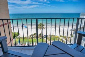 A balcony with a view of a beach, featuring a railing and a few lounge chairs. - Sunshine Condo #4A Beachfront Perfection (Indian Shores)