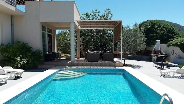 A modern outdoor pool area with a pergola, seating, and a barbecue setup. - Apartments Villa Dona (Vela Luka)