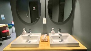 A modern bathroom with two sinks, two mirrors, and two red stools. - Shinjuku Nikka Hotel - Hostel  (Tokyo)