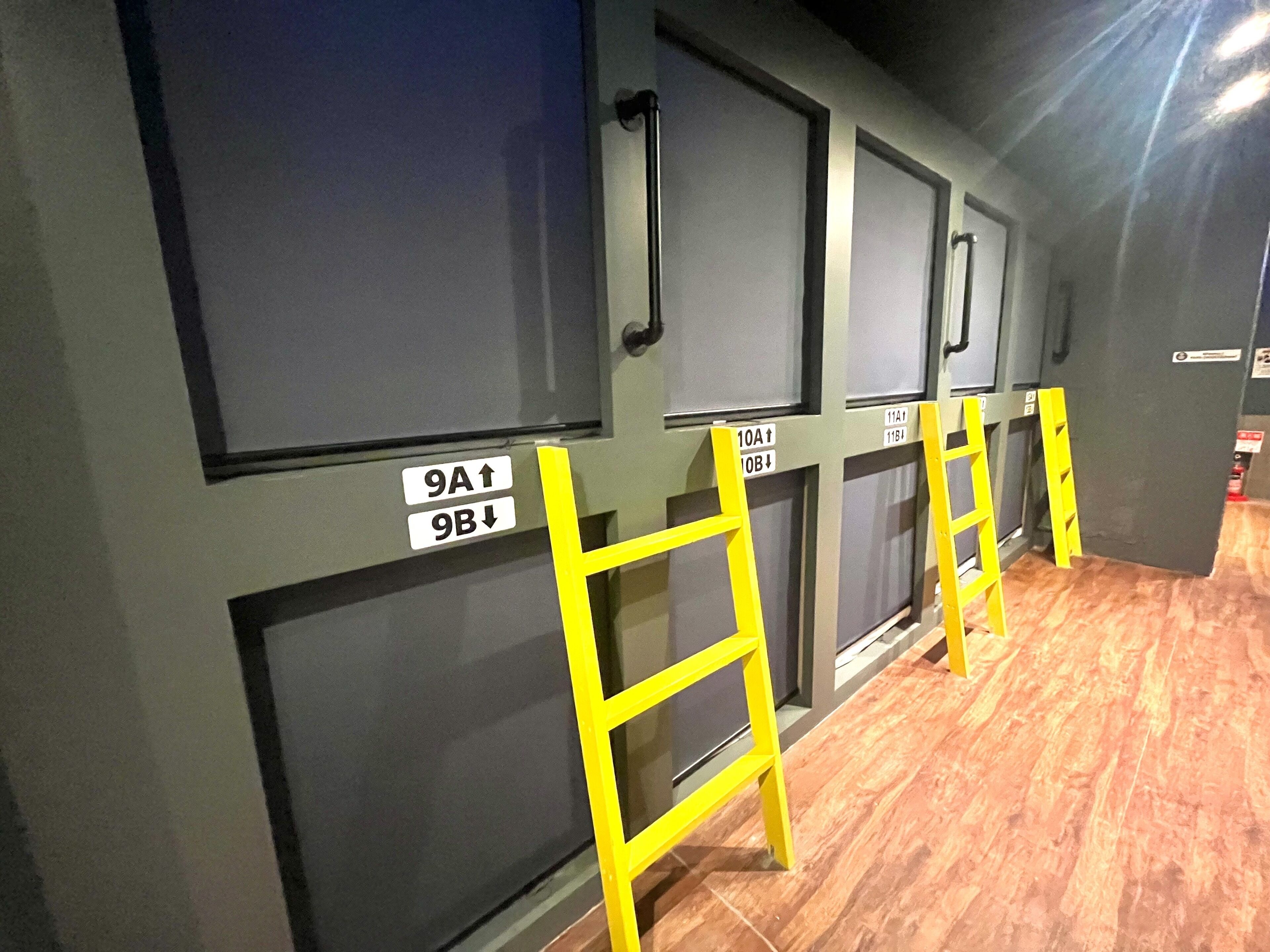 A row of rooms with numbered doors and yellow ladders.