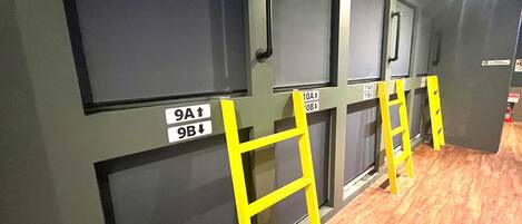 A row of rooms with numbered doors and yellow ladders.