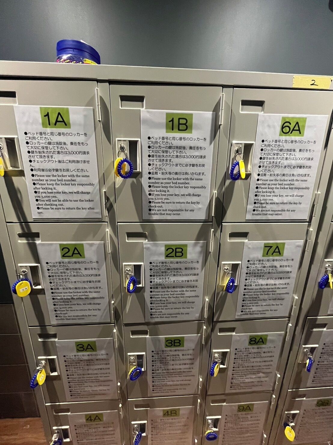A row of metal lockers with numbered labels and instructions in Japanese.