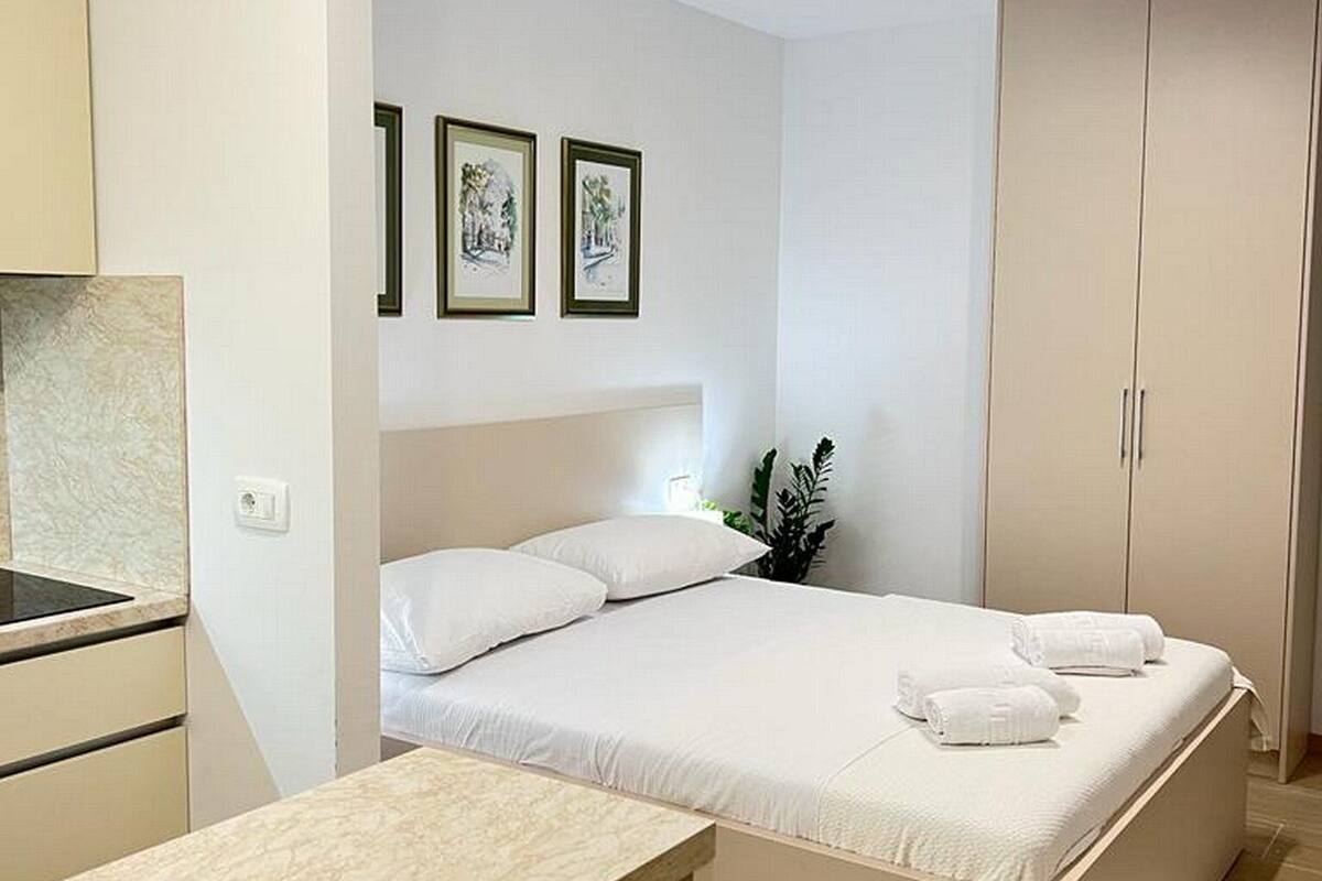 A compact bedroom with a bed, a desk, and a wardrobe.