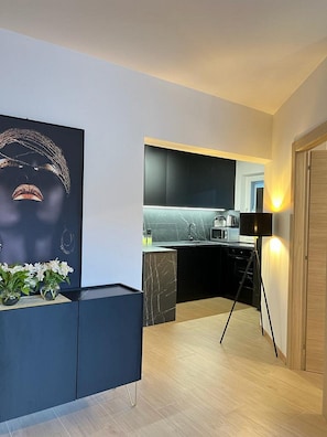 A modern kitchen with dark cabinetry, a black countertop, and a standing lamp. - Apartments Jelena (Dubrovnik)