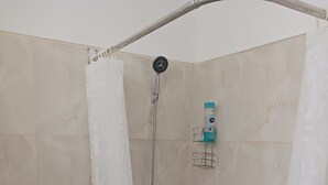 A small, enclosed shower area with a toilet and a soap dispenser.