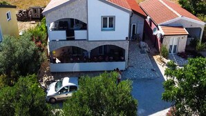 Una casa de dos pisos con techo rojo, un balcón y una entrada para coches.