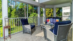 A covered patio with wicker furniture, a table, and a lantern.