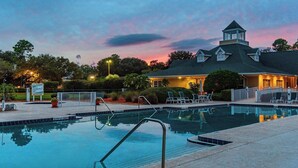 A swimming pool with a view of a building with a tower and a covered area.