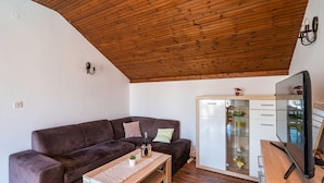 A living room with a brown leather sofa, a wooden coffee table, a flat-screen TV, and a glass-fronted cabinet with drawers. - Apartment Dorica (Dubrovnik)
