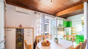 A dining area with a round table, chairs, and a fruit bowl centerpiece. There is a glass cabinet with decorative items and a wooden ceiling. - Apartment Dorica (Dubrovnik)