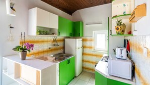 A compact kitchen with green and white cabinets, a white refrigerator, and a microwave. - Apartment Dorica (Dubrovnik)