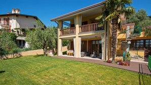 A two-story house with a balcony, a lawn, and a palm tree. - Crocus 1 con piscina by Wonderful Italy (Soiano del Lago)