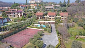 A residential area with houses, a tennis court, and a swimming pool. - Crocus 1 con piscina by Wonderful Italy (Soiano del Lago)