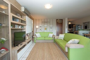 Appartement, uitzicht op zwembad | Woonruimte | Een 32-inch flatscreentelevisie met kabelzenders