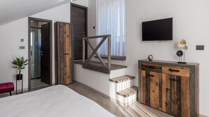 A modern bedroom with a large bed, a wooden staircase, a TV, and a minimalist decor. - Villa Corichi (Opatija)