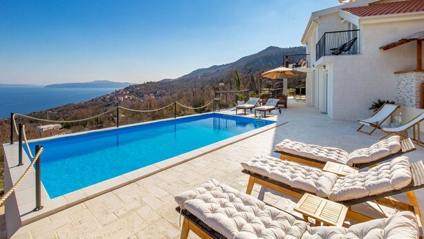 A swimming pool with lounge chairs and a view of the sea and mountains. - Villa Corichi (Opatija)
