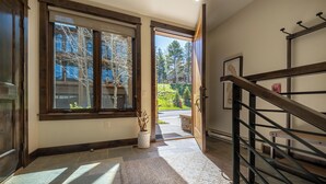 A hallway with a wooden floor, a stone wall, and a staircase with a metal railing.