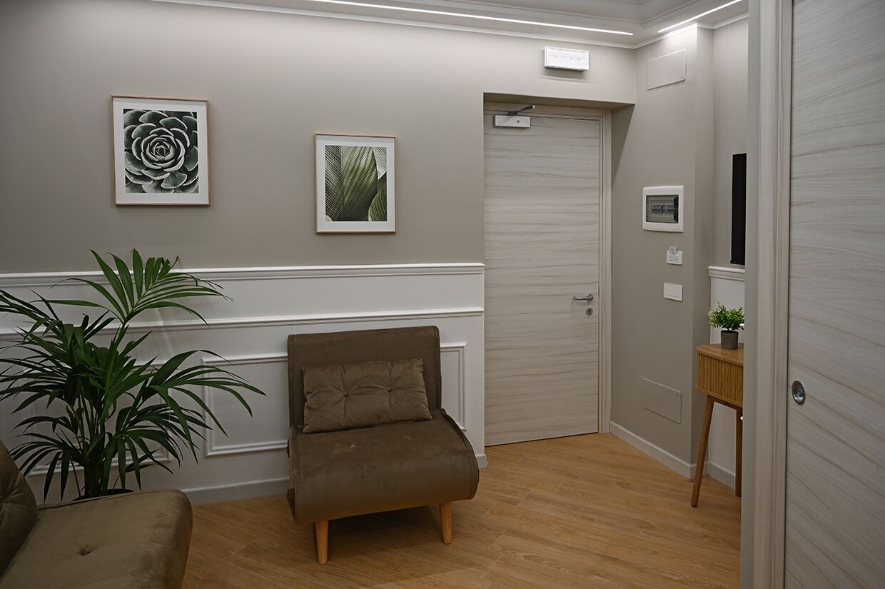 Una habitación con un sofá marrón, una planta en maceta y dos cuadros en la pared.