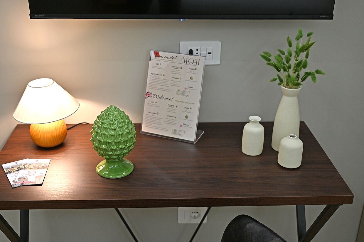 A wooden table with a lamp, a welcome sign, a green decorative item, and white vases.