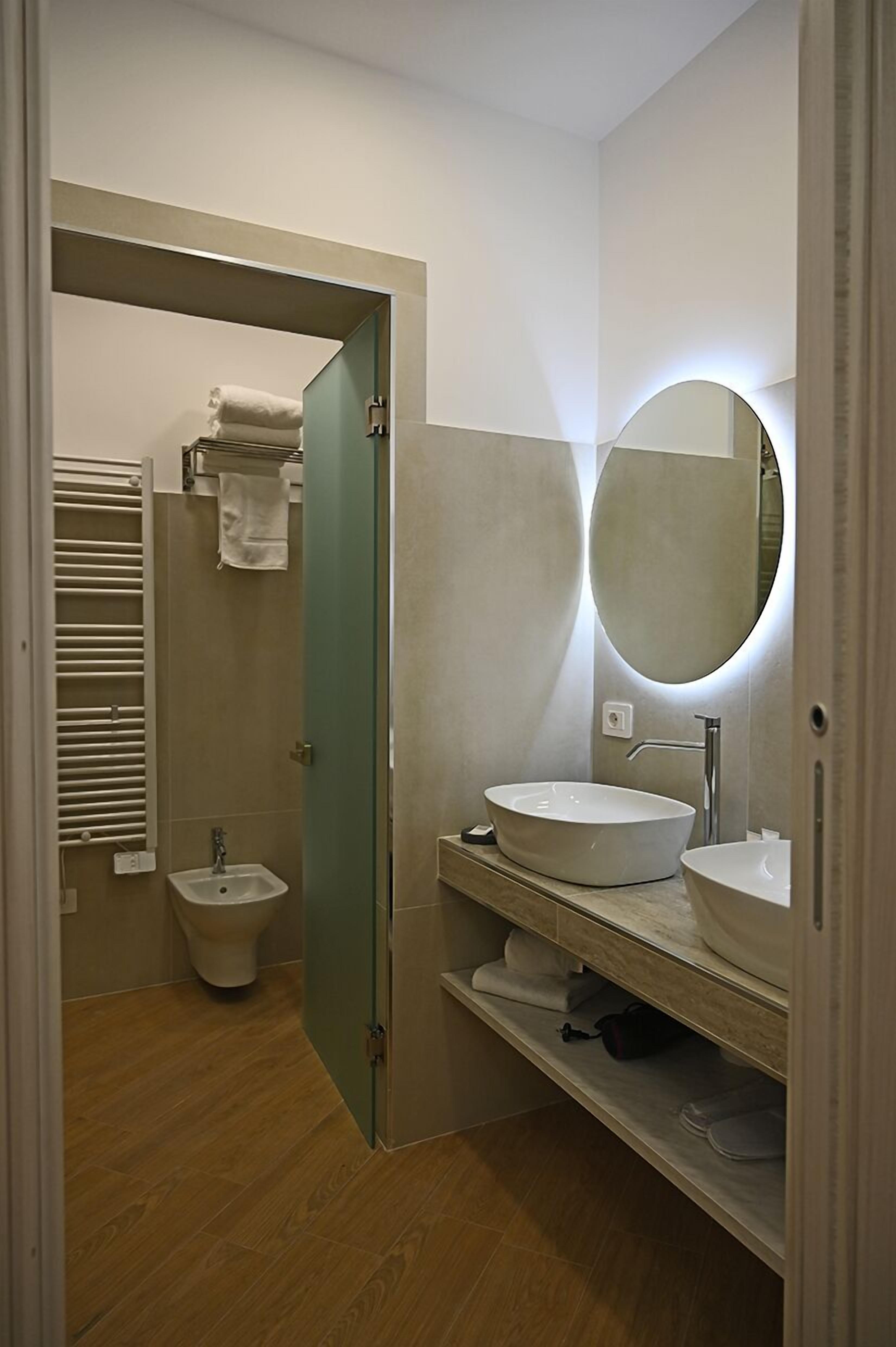 Une salle de bain moderne avec une baignoire sur pieds, un miroir rond et des toilettes.