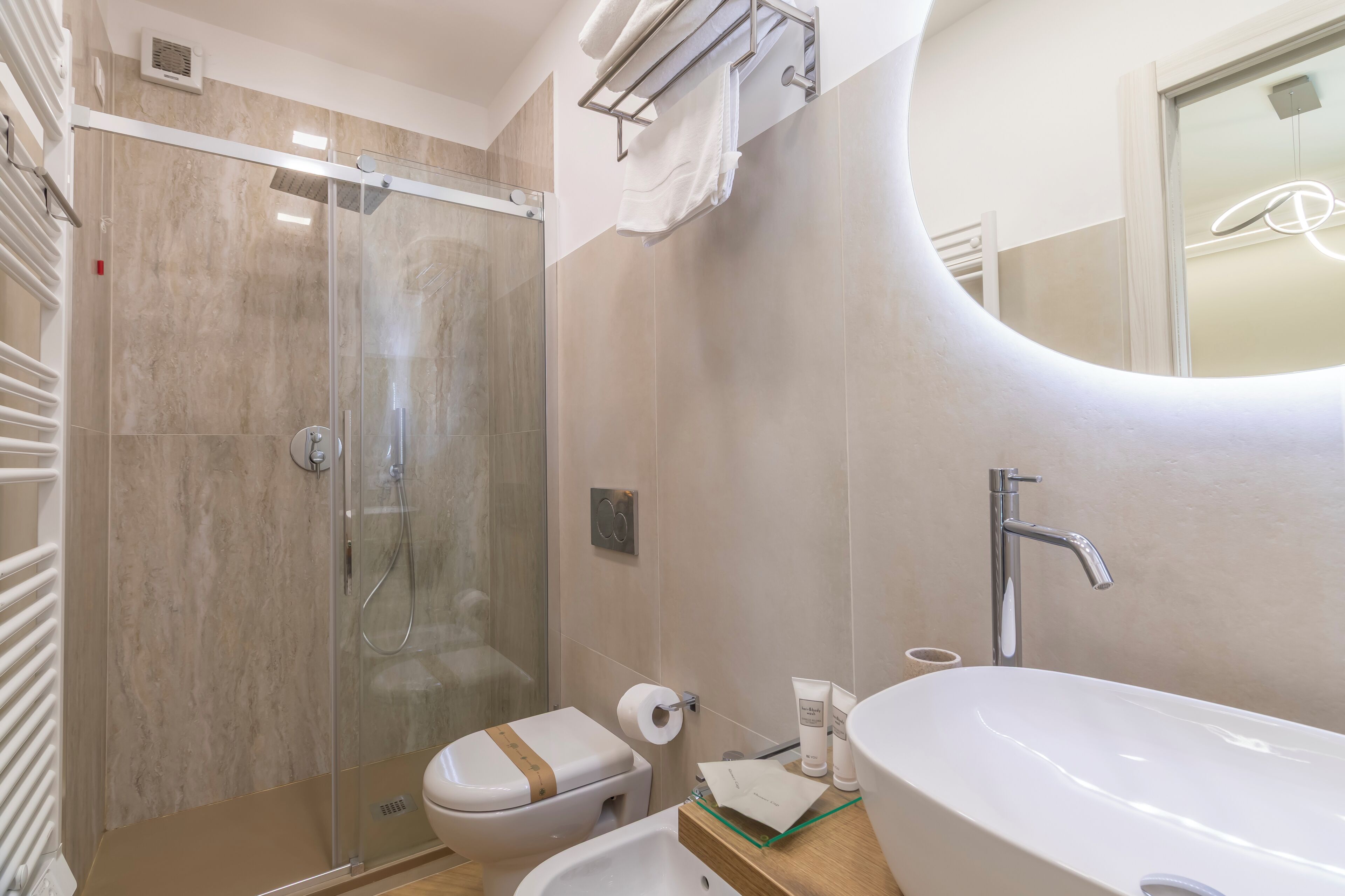 Een moderne badkamer met een douchecabine van glas, een toilet, een wastafel en een spiegel.