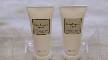 Dos tubos de jabón para cabello y cuerpo y dos paquetes de jabón natural sobre un expositor transparente.
