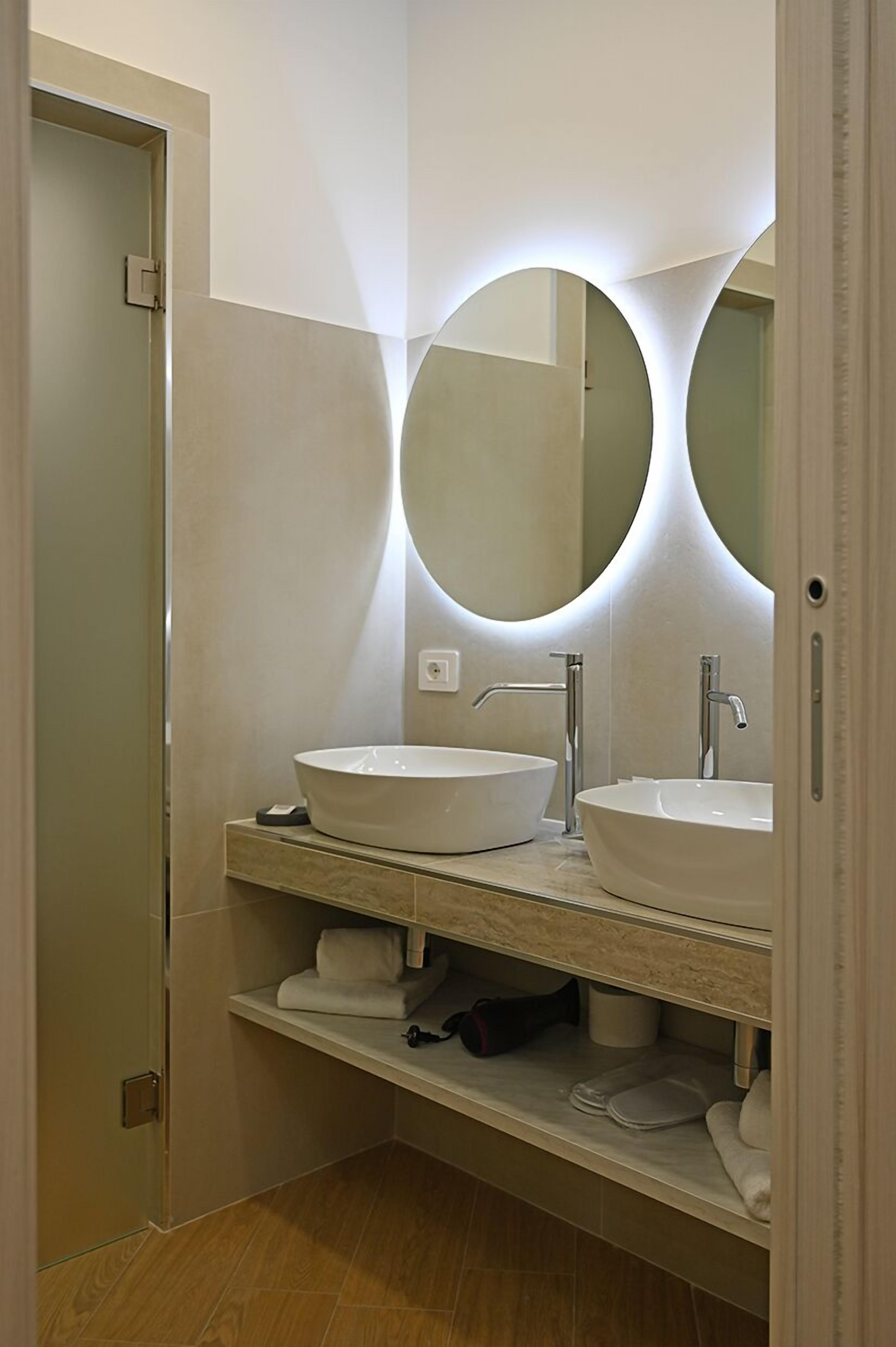 Un baño moderno con dos lavamanos blancos, un espejo grande y un perchero para toallas.