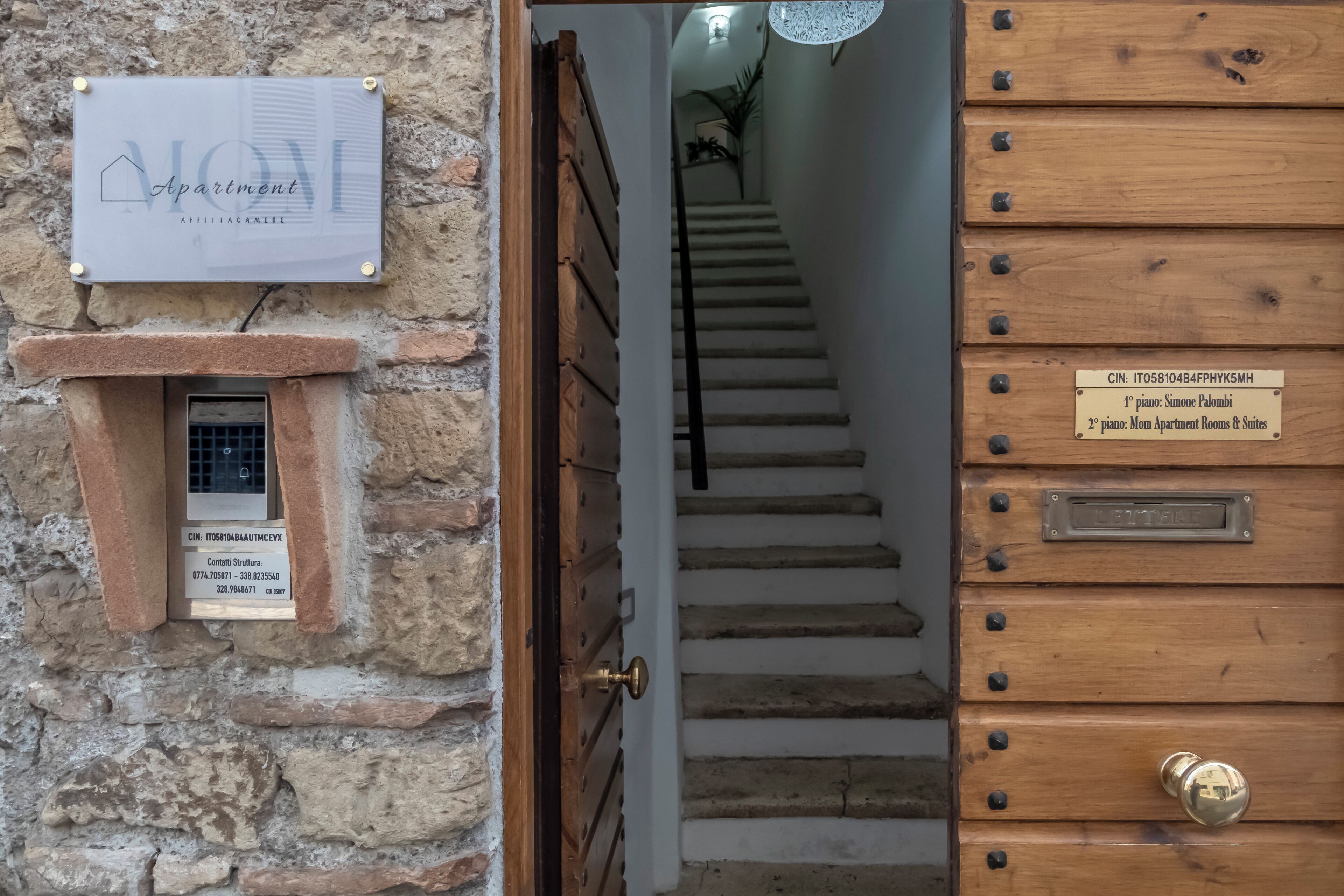 A staircase leading to a wooden door with a metal plate indicating room numbers.