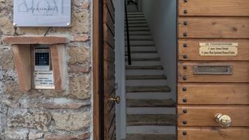 A staircase leading to a wooden door with a metal plate indicating room numbers.