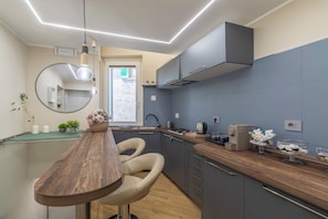 A modern kitchen with a wooden dining table, two chairs, a round mirror, and a built-in stove.