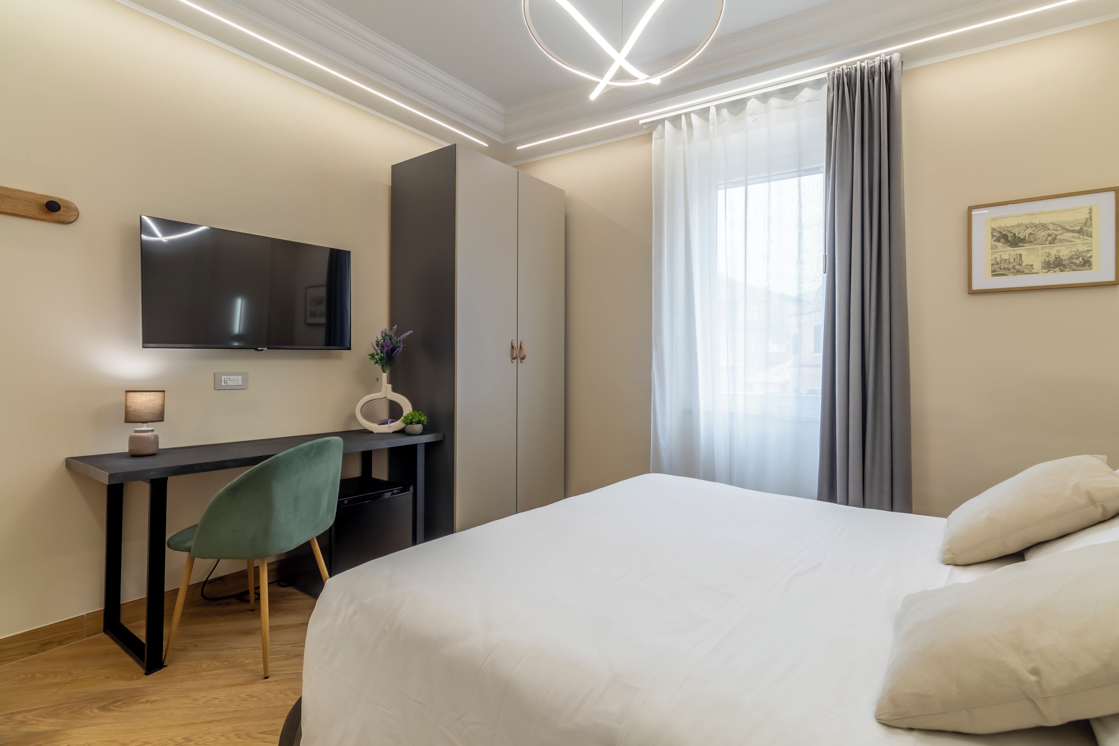 A hotel room with a bed, a desk, a chair, a TV, and a window with curtains.