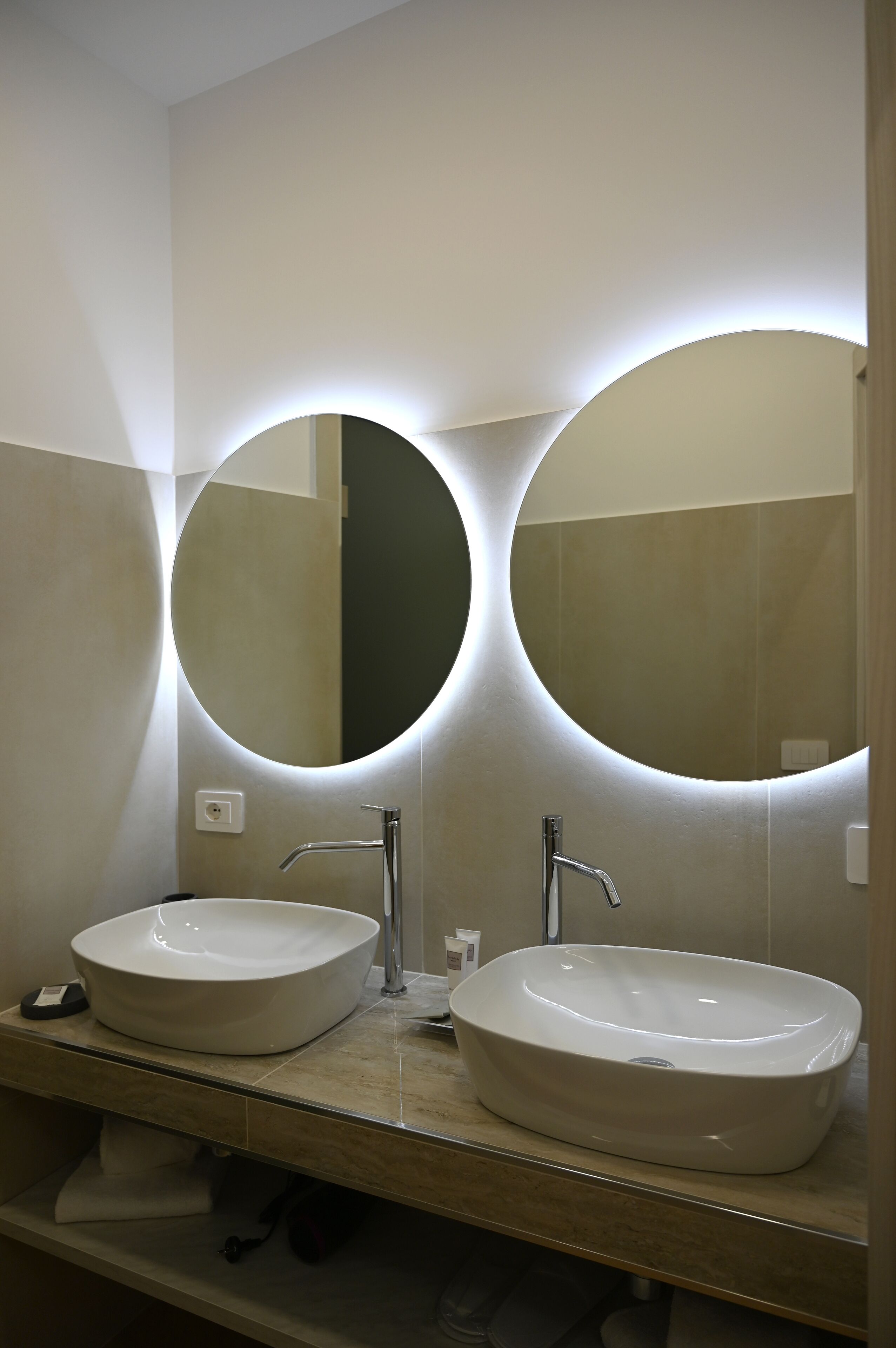Une salle de bain avec deux miroirs ronds, un lavabo et un porte-serviettes.