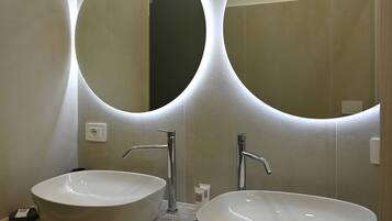 Une salle de bain avec deux miroirs ronds, un lavabo et un porte-serviettes.