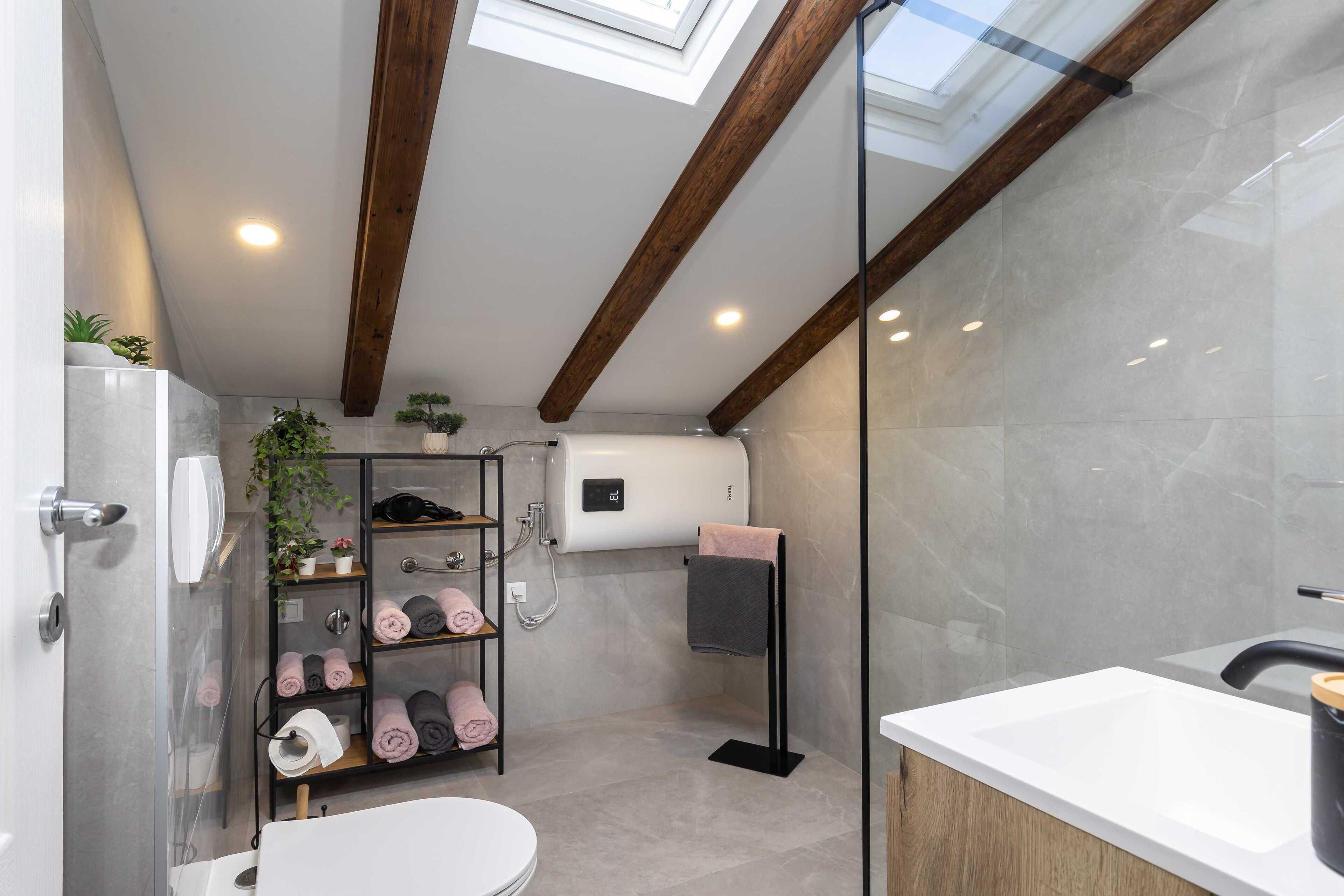 Une salle de bain moderne dotée d’une lucarne, de toilettes, d’un lavabo et d’un porte-serviettes.