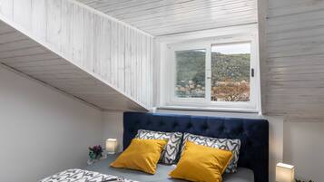 A bedroom with a bed, two yellow pillows, a window with a view of a hillside, and a wooden ceiling.