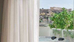 Un balcón con hidromasaje, vistas a un edificio histórico y una planta en maceta.