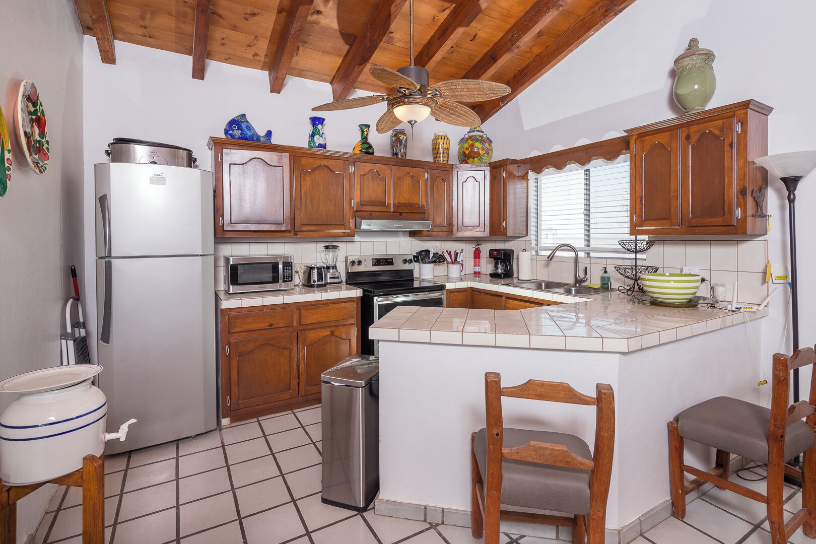 A kitchen with wooden cabinets, a refrigerator, a microwave, a stove, and a sink.