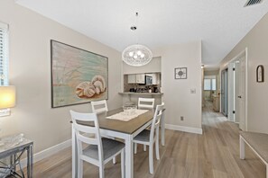 Un coin repas comprenant une table, des chaises, un lustre et un tableau accroché au mur.