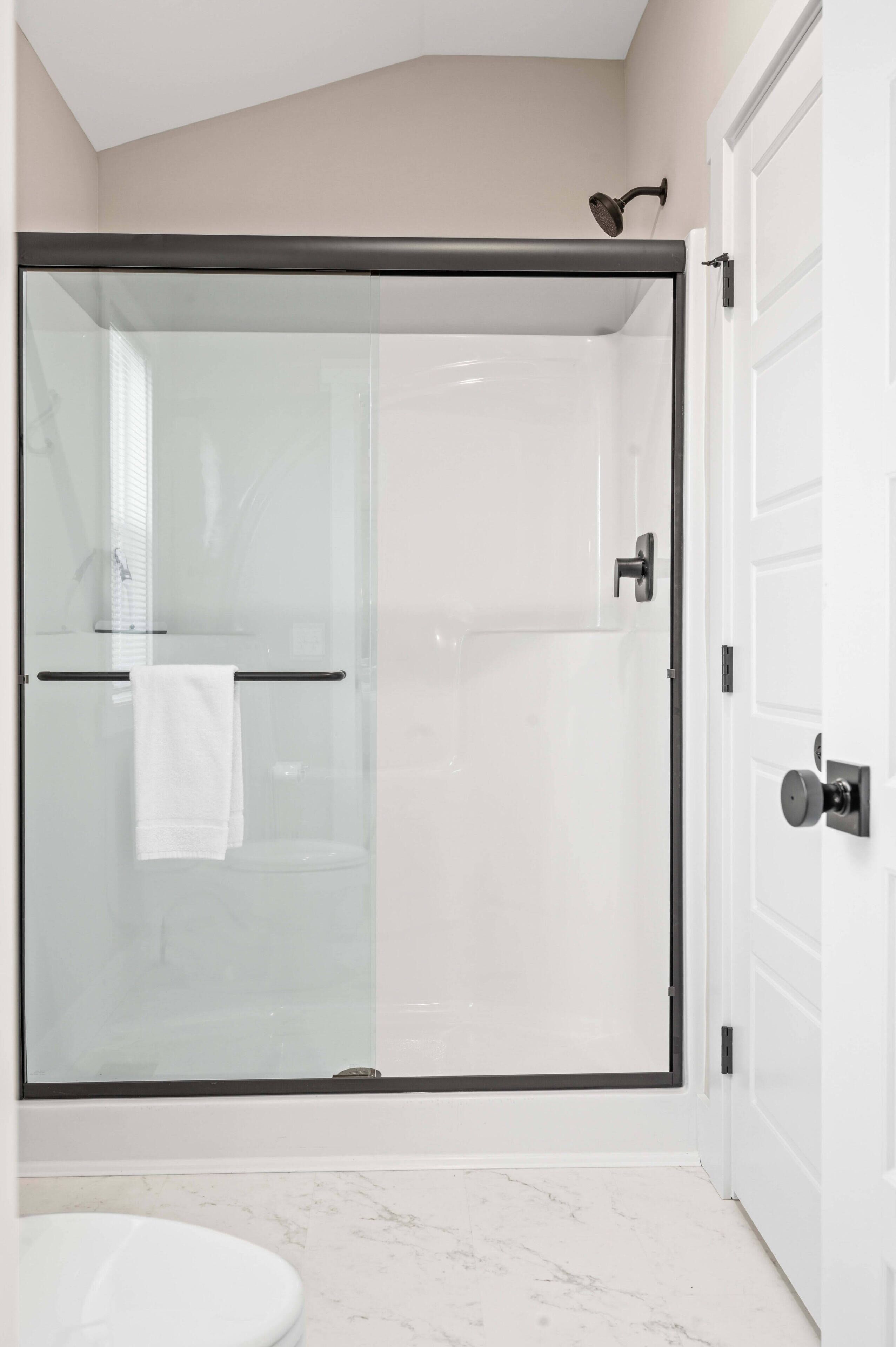 Une salle de bain moderne avec une douche à parois de verre, des toilettes blanches et un sol en marbre.