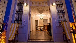 Ein imposanter Eingangsbereich mit Treppe, einer Chandelier und einem Essbereich mit Stühlen und Tisch.