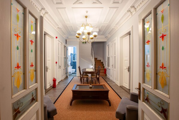 A hallway with a staircase, a dining area with a table and chairs, and a fire extinguisher on the wall.