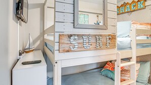 Una cama individual con cabecera de madera que muestra la palabra "SHACK" y un espejo.