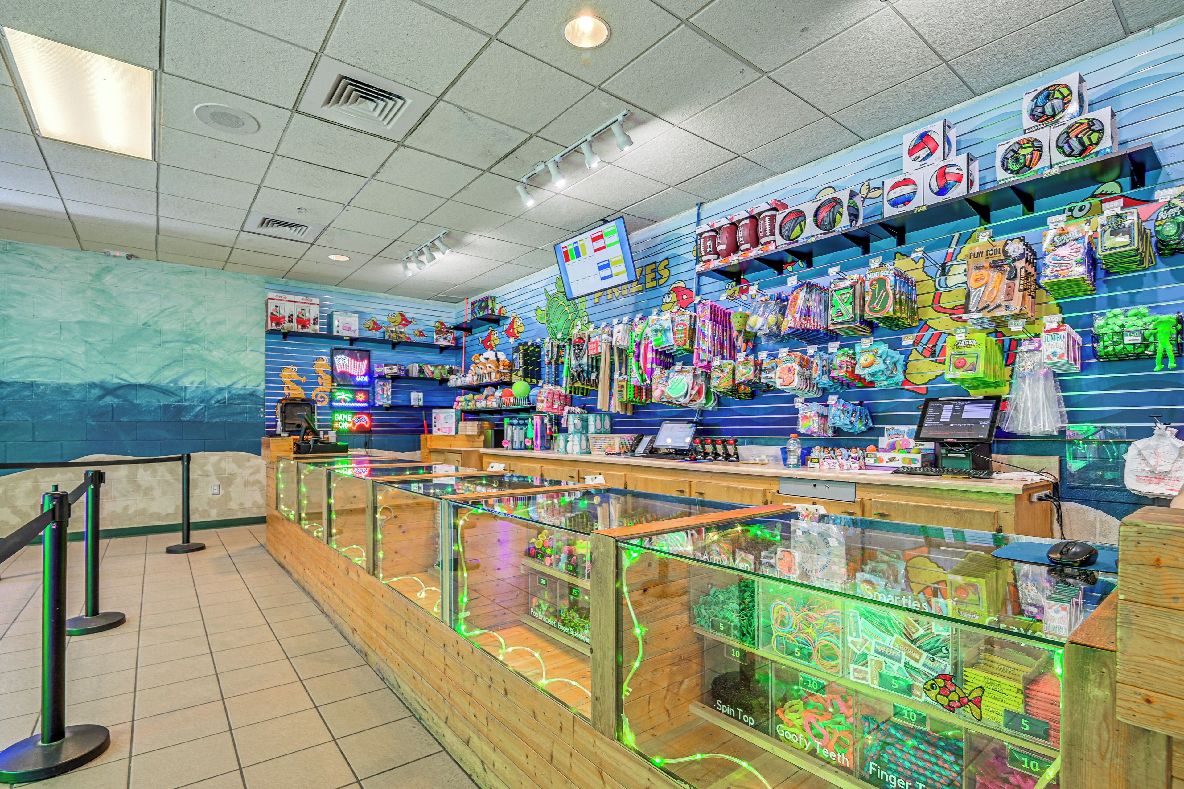 A brightly lit indoor market with various stalls selling toys and games.