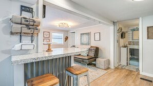 Una cocina moderna con encimera de granito, taburetes de bar y un perchero para toallas.