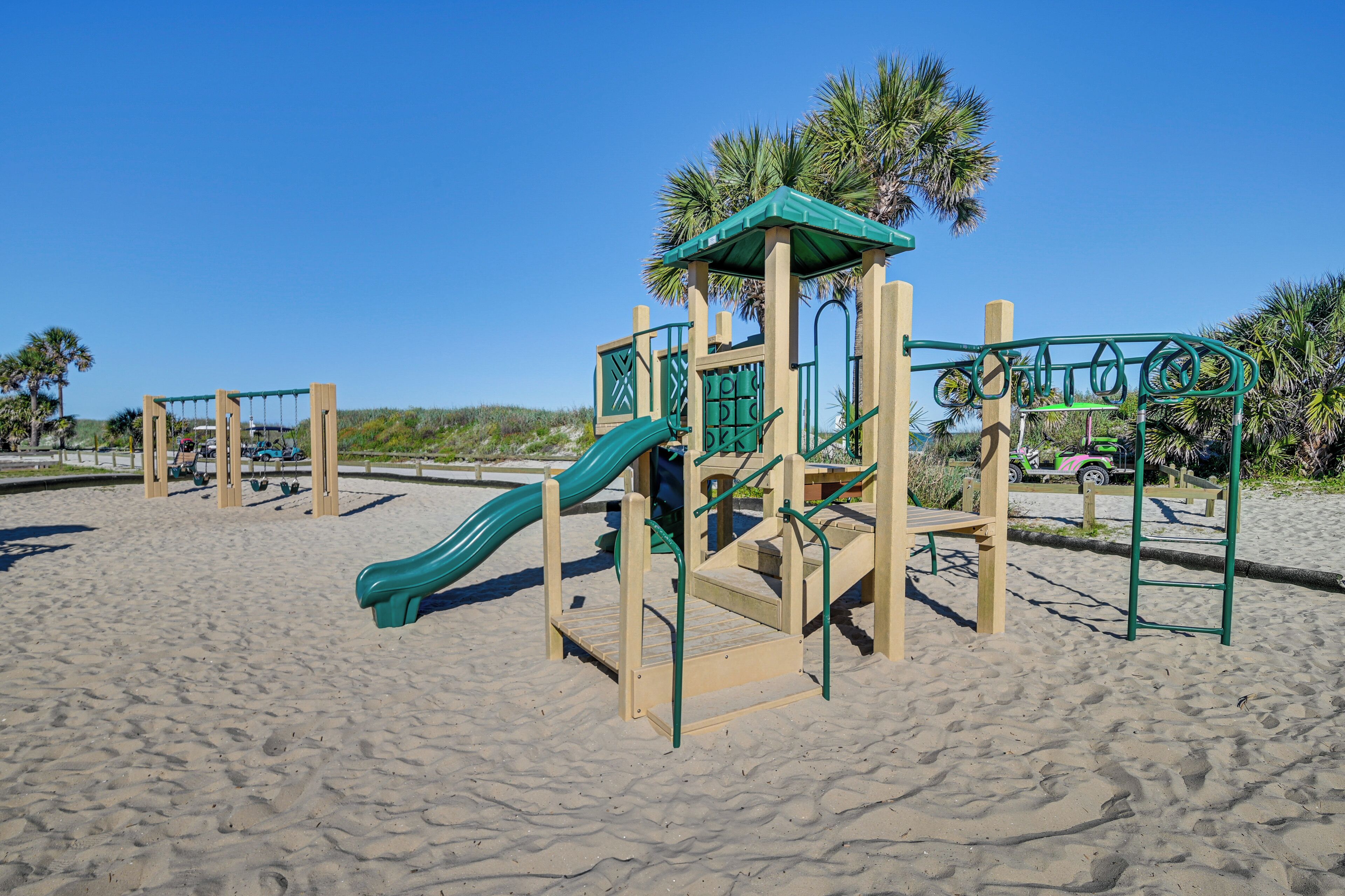 Ein Spielplatz mit Rutsche und Klettergerüsten auf Sandboden.